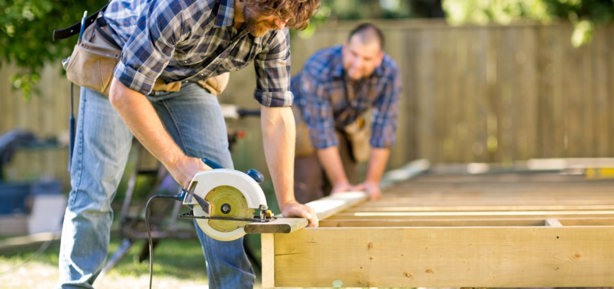 Two men happily building a timber deck together.